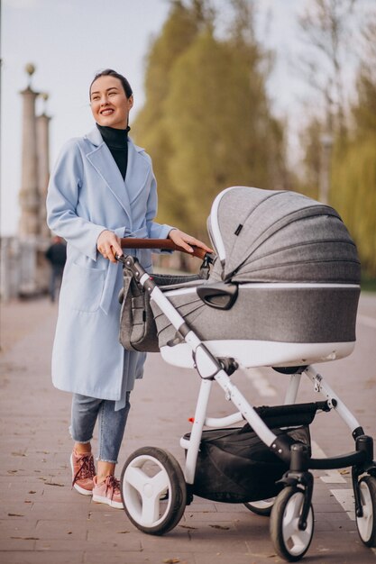 Young mother walking with baby carriage in park