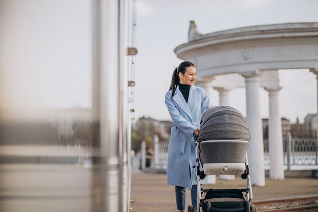 Young mother walking with baby carriage in park