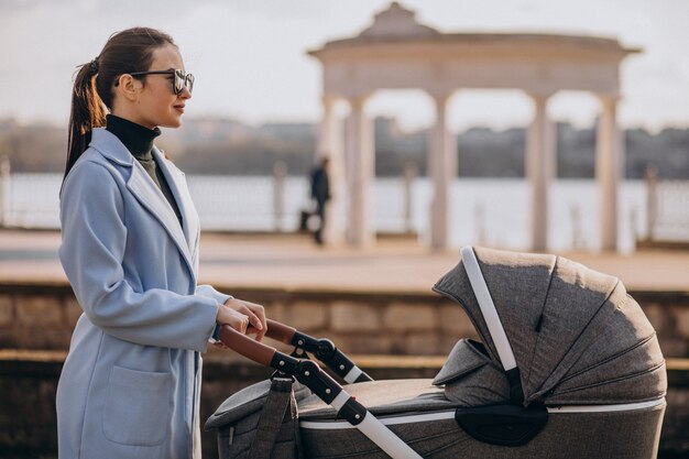 Young mother walking with baby carriage in park