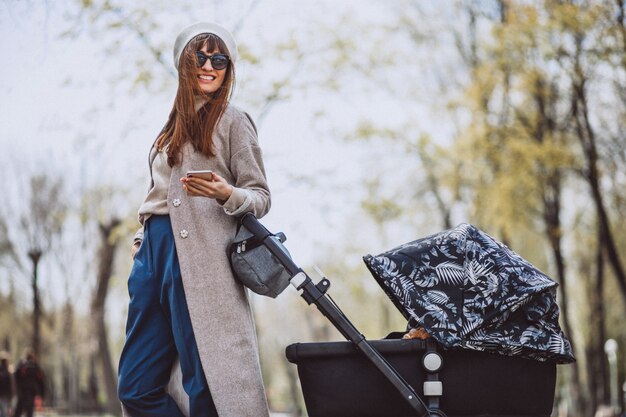 Young mother walking with baby carriage in park