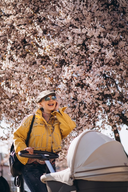 Free photo young mother walking with baby carriage in park