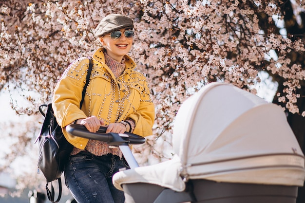 Young mother walking with baby carriage in park