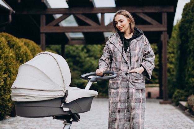 Young mother walking with baby carriage in park