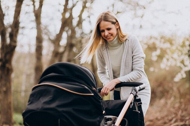 Young mother walking with baby carriage in park