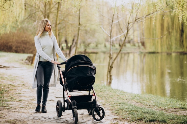 Молодая мать гуляет с коляской в парке