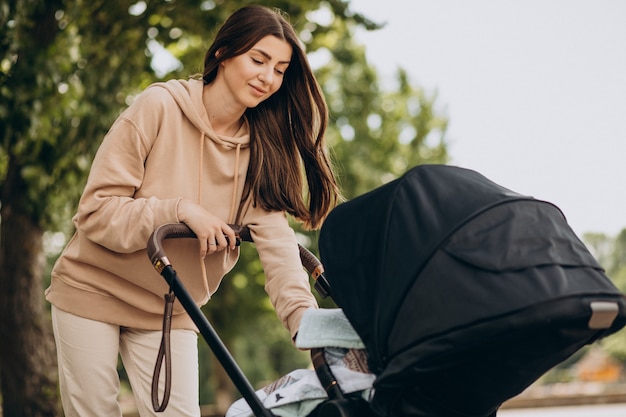 Free photo young mother walking with baby carriage in park