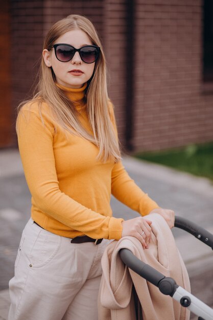 Young mother walking with baby stroller