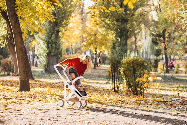 가을 공원에서 산책하는 아기 딸과 함께 젊은 어머니