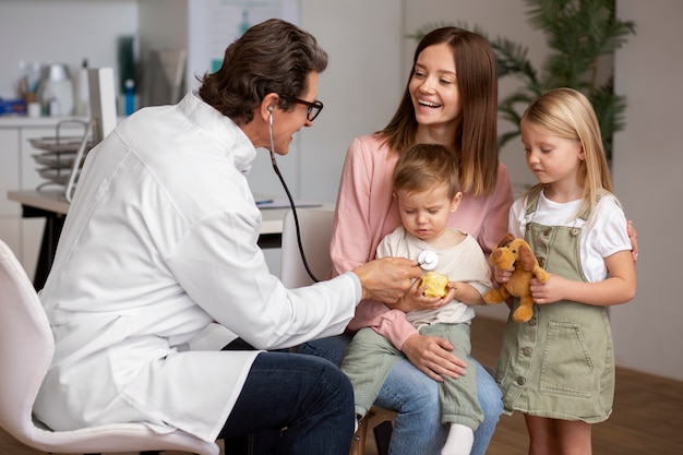 Foto gratuita giovane madre con i suoi figli a un appuntamento dal pediatra