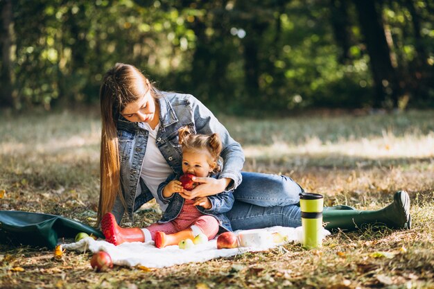 Young mother with her little daughter in an autumn park having picnic