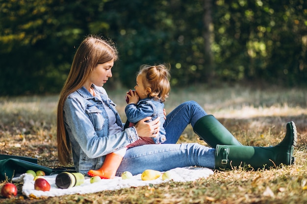 Young mother with her little daughter in an autumn park having picnic