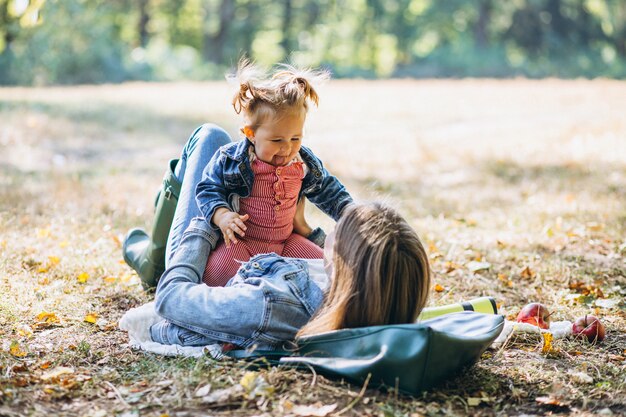 ピクニックを持つ秋の公園で彼女の小さな娘を持つ若い母親