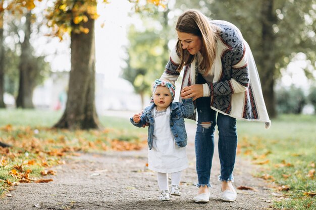 Young mother with her little daughter in an autumn park