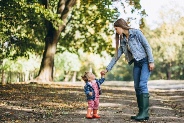 秋の公園で彼女の小さな娘を持つ若い母親