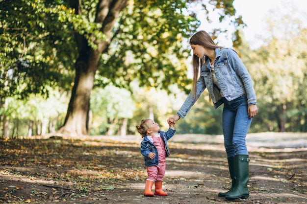 Молодая мать с маленькой дочерью в осеннем парке