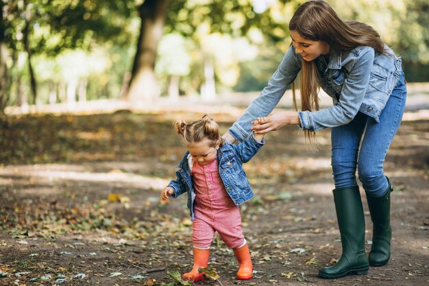秋の公園で彼女の小さな娘を持つ若い母親