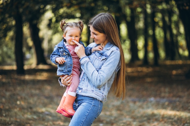 Young mother with her little daughter in an autumn park