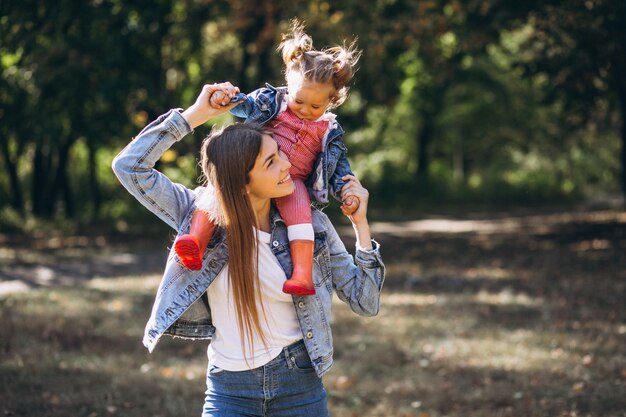 Young mother with her little daughter in an autumn park