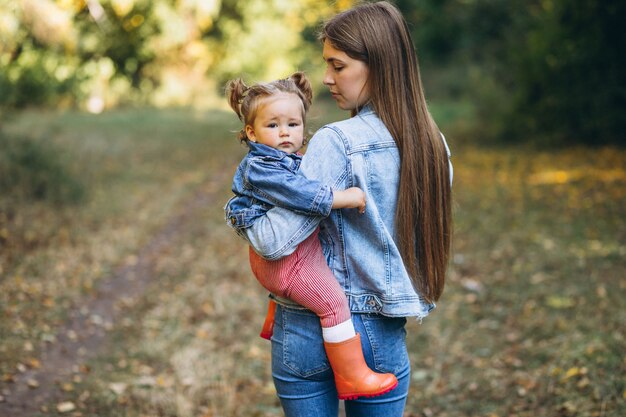 Young mother with her little daughter in an autumn park