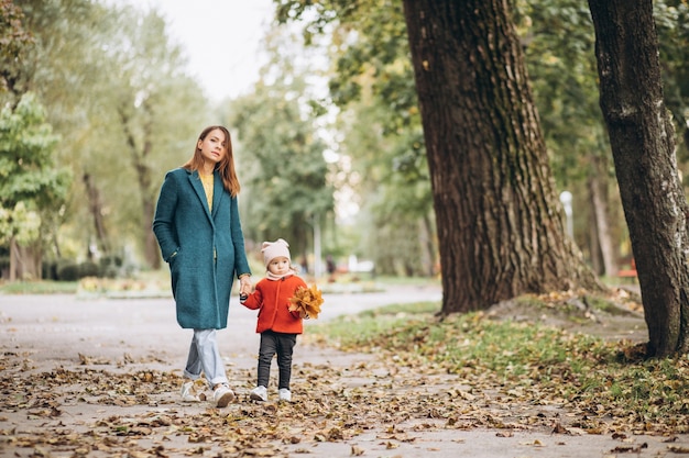 Young mother with her little daughter in an autumn park