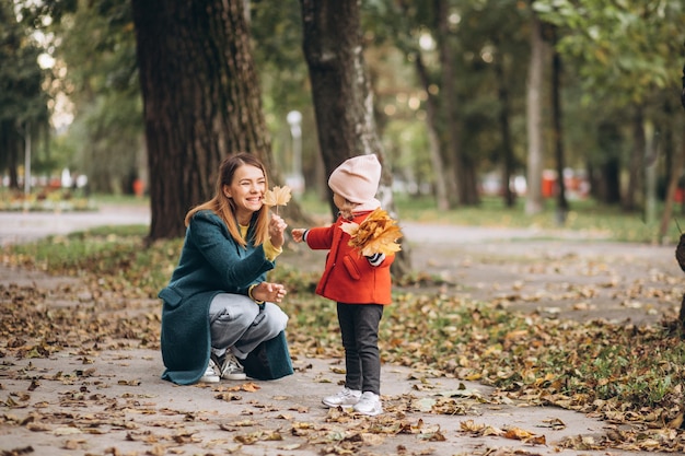 Young mother with her little daughter in an autumn park