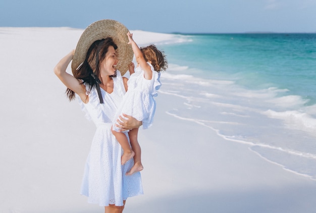 Young mother with her little daughter at the beach by the ocean