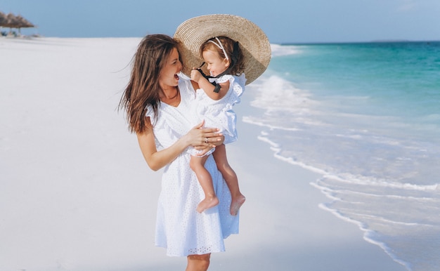 Young mother with her little daughter at the beach by the ocean