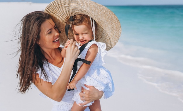 Young mother with her little daughter at the beach by the ocean