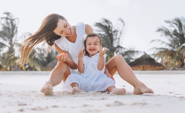 Young mother with her little daughter at the beach by the ocean