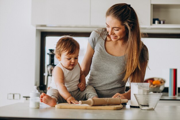 キッチンで料理をして彼女の幼い息子を持つ若い母親