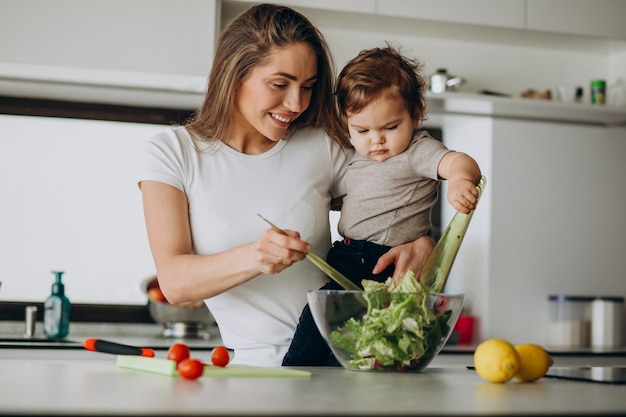 Молодая мать с сыном делает салат на кухне