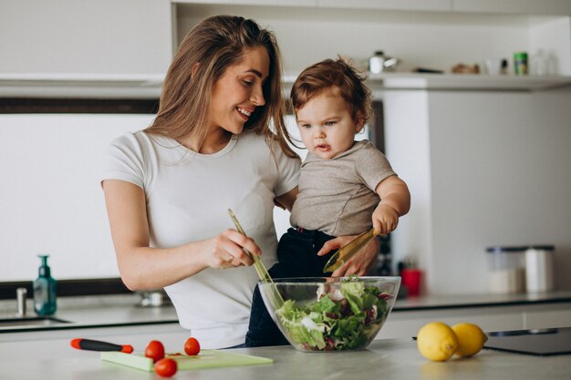 Young mother with her little son making salad at kitchen