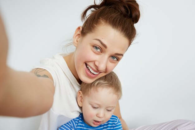 Young mother with her one years old little son dressed in pajamas are posing