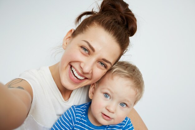 Young mother with her one years old little son dressed in pajamas are posing