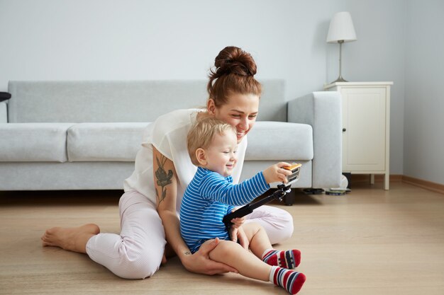 Young mother with her one years old little son dressed in pajamas are posing