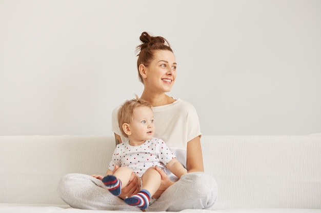 Young mother with her one years old little son dressed in pajamas are relaxing