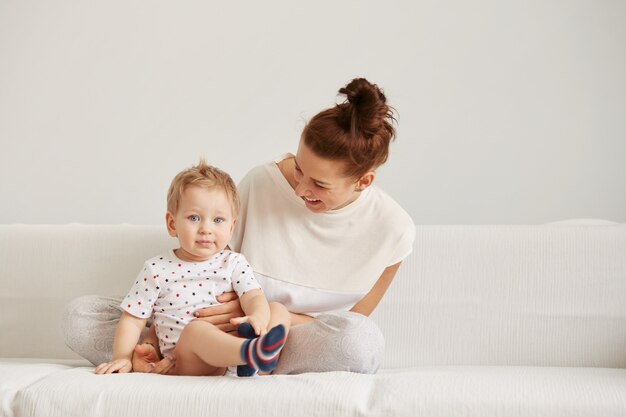 Young mother with her one years old little son dressed in pajamas are relaxing