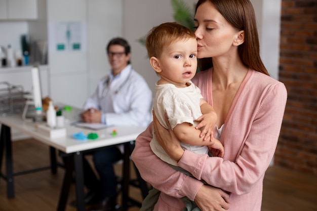 Foto gratuita giovane madre con il suo bambino dal pediatra per un esame fisico