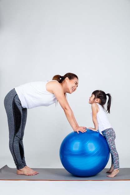Young mother with little daughter exercise on fitness ball