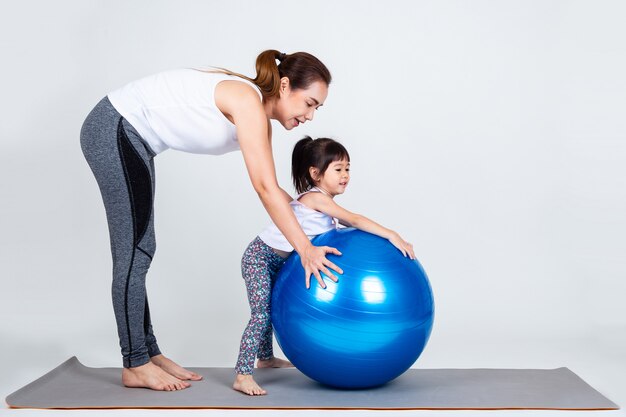Young mother with little daughter exercise on fitness ball