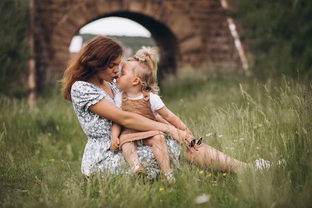 Giovane madre con la piccola figlia nel parco che si siede sull'erba