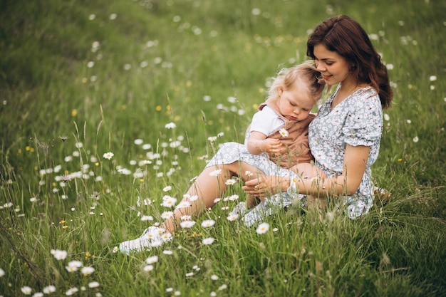 Young mother with little daughter in park sitting on grass