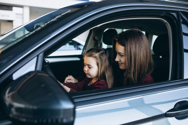 Young mother with little daughter sitting inside a car