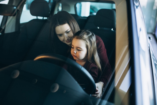 Young mother with little daughter sitting inside a car