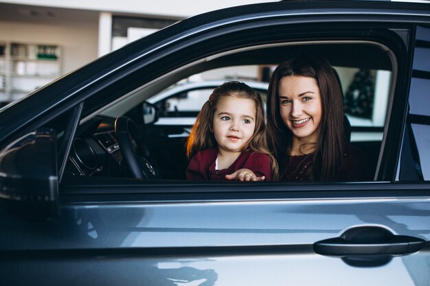 車の中に座っている小さな娘を持つ若い母親