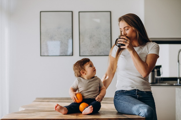 Young mother with little son drinking water at home