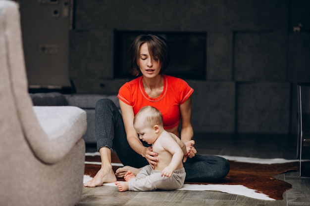 Молодая мать с маленьким сыном, практикующих йогу дома
