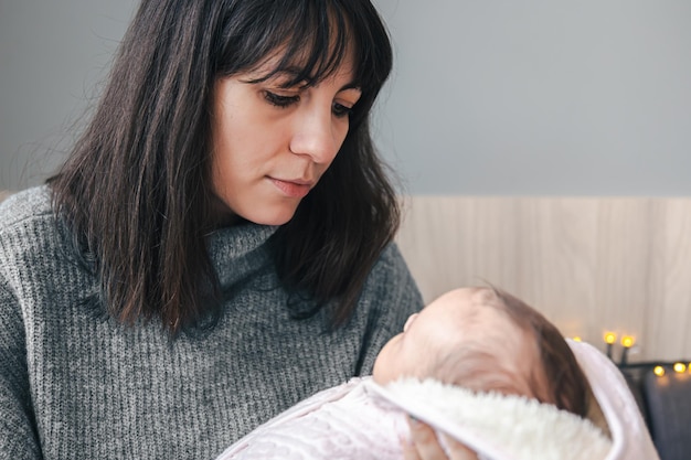 Free photo a young mother with a newborn baby girl in her arms