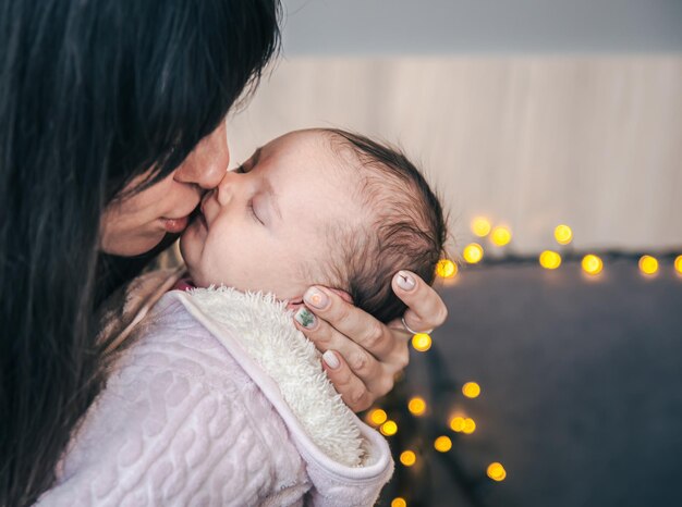 生まれたばかりの女の赤ちゃんを腕に抱えた若い母親