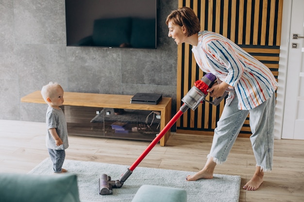 幼児の息子が家で掃除をしている若い母親
